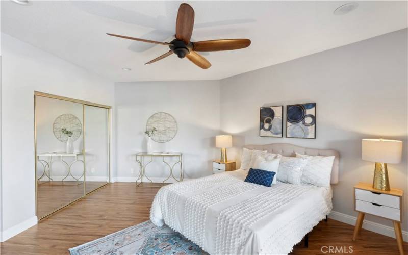 Primary bedroom has ceiling fan and dual closets with mirrored doors.