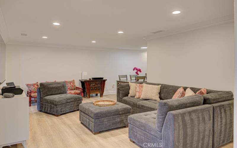 Note the neutral flooring, smooth ceiling and recessed lighting in the living room. Dining area can be seen in the background.