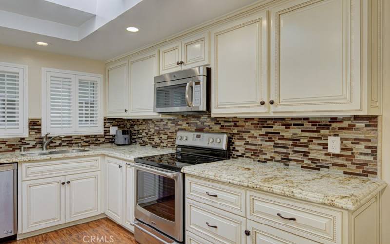 Elegant custom cabinetry, granite counters and glass tile backsplash.