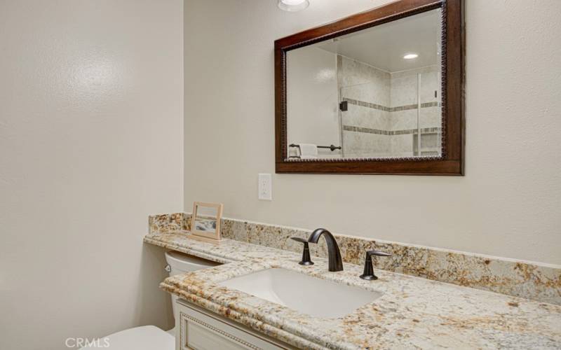 The guest bathroom has a large vanity with custom cabinets.