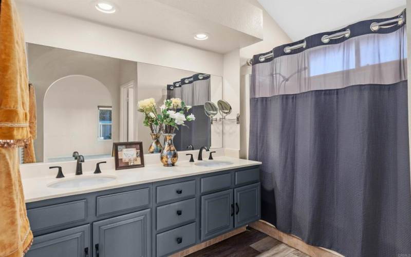 Primary bathroom -generous proportions, dual vanity and wood tile plank flooring.