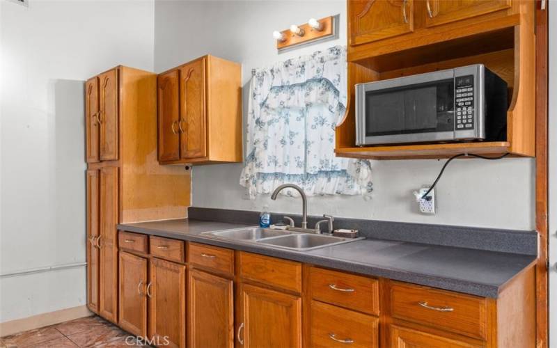 Kitchen sink area with pantry style cabinet and storage cabinets