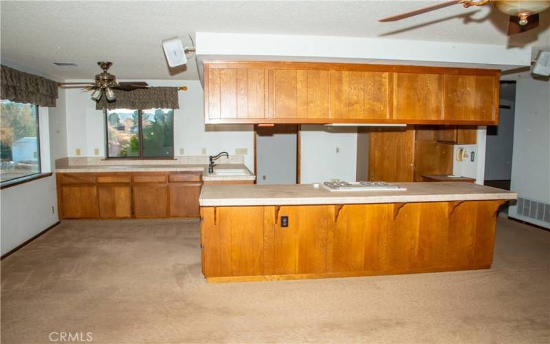 The kitchen with island is adjacent to the living room with stone faced fireplace.  Kitchen also includes tile counters, gas range, dishwasher, dining area, island, breakfast bar and stunning views of the mountains.