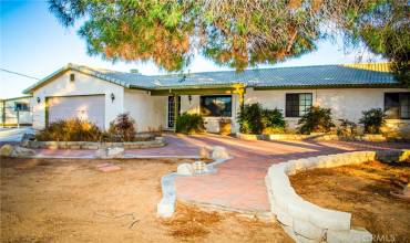 Front of the home showing tile roof, paver stones, mature landscaping and covered porch.