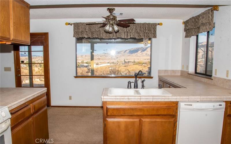 Kitchen with tile counters, gas range, dishwasher, dining area, island, breakfast bar and stunning views of the mountains.