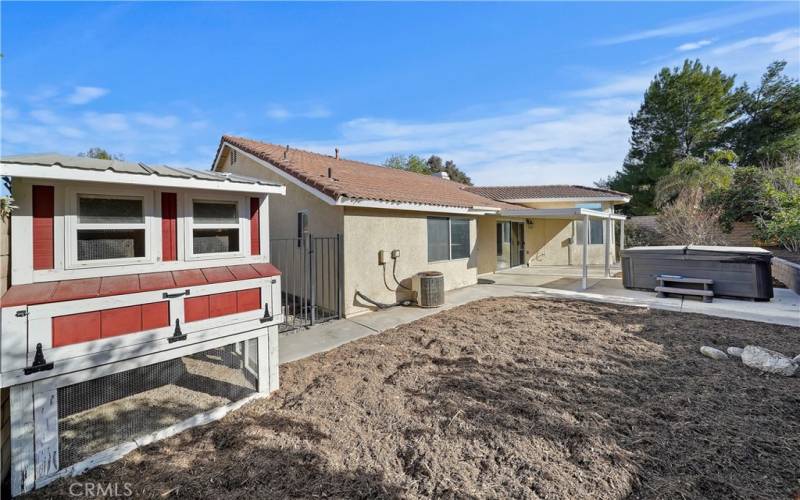 Backyard has a covered patio, a chicken coop, a hot tub, and plenty of open space