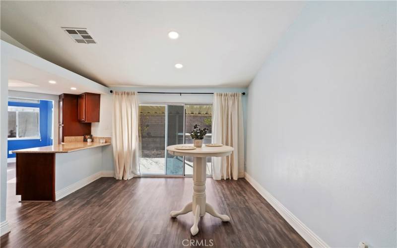 Features a bright and open dining area with large sliding glass doors leading to the backyard. The space is enhanced by wood-style flooring, recessed lighting, and a neutral color palette