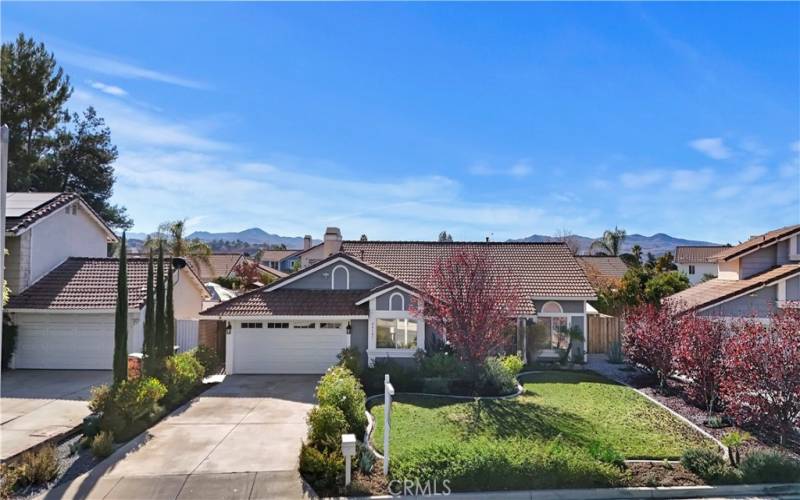 Front shot of the home showcasing the tiled roof, a well-maintained front yard, and a driveway leading to a two-car garage.