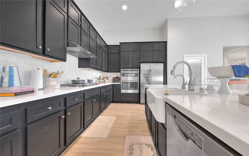 Stovetop and dual ovens next to refrigerator