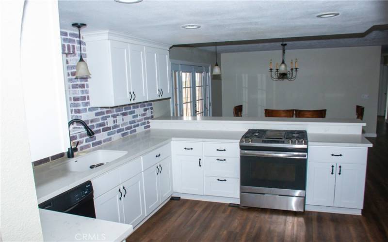 Kitchen with Quartz counters, modern white cabinets, custom backsplash, breakfast bar and stainless/black appliances.