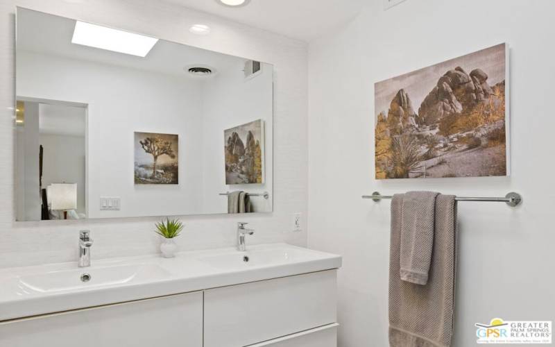 A double vanity in the primary bathroom has plenty of bright light flowing in through a skylight.