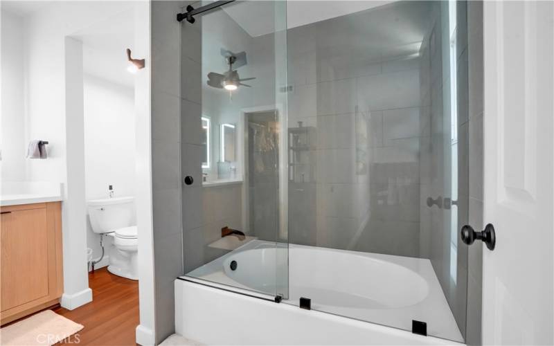 Tub with glass shower doors in primary ensuite.