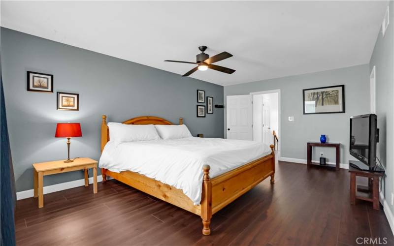 Primary bedroom with ceiling fan and LVF flooring.