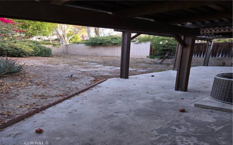 View of the backyard, coming around the corner from the front doors with the covered patio in view
