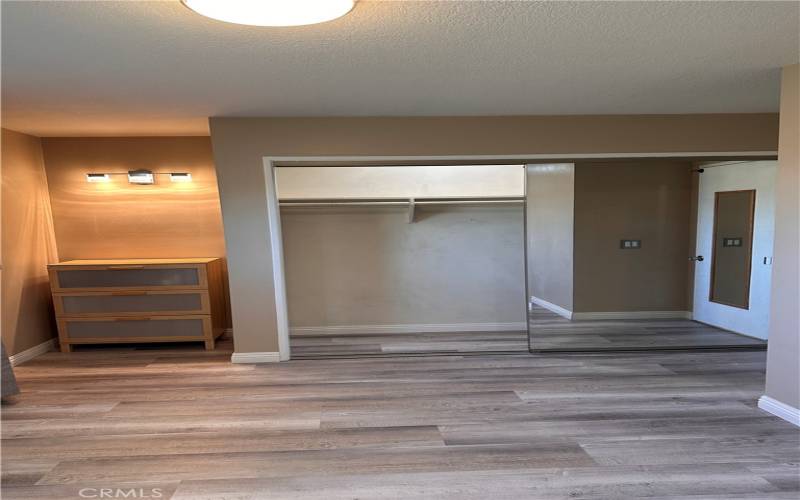 First bedroom with dresser and mirrored closet with light inside.