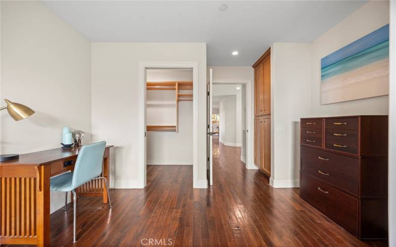 This view of the secondary suite shows space to work remotely from home. You can see inside the walk in closet with built in organizers.